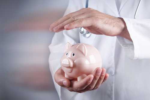 Arzt hält Hand über Sparschwein